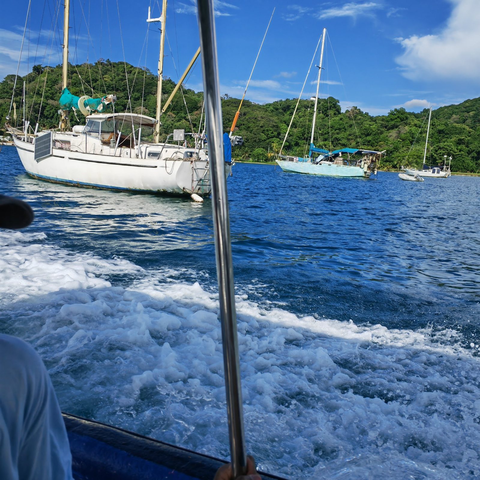 Boat ride past anchored sailboats